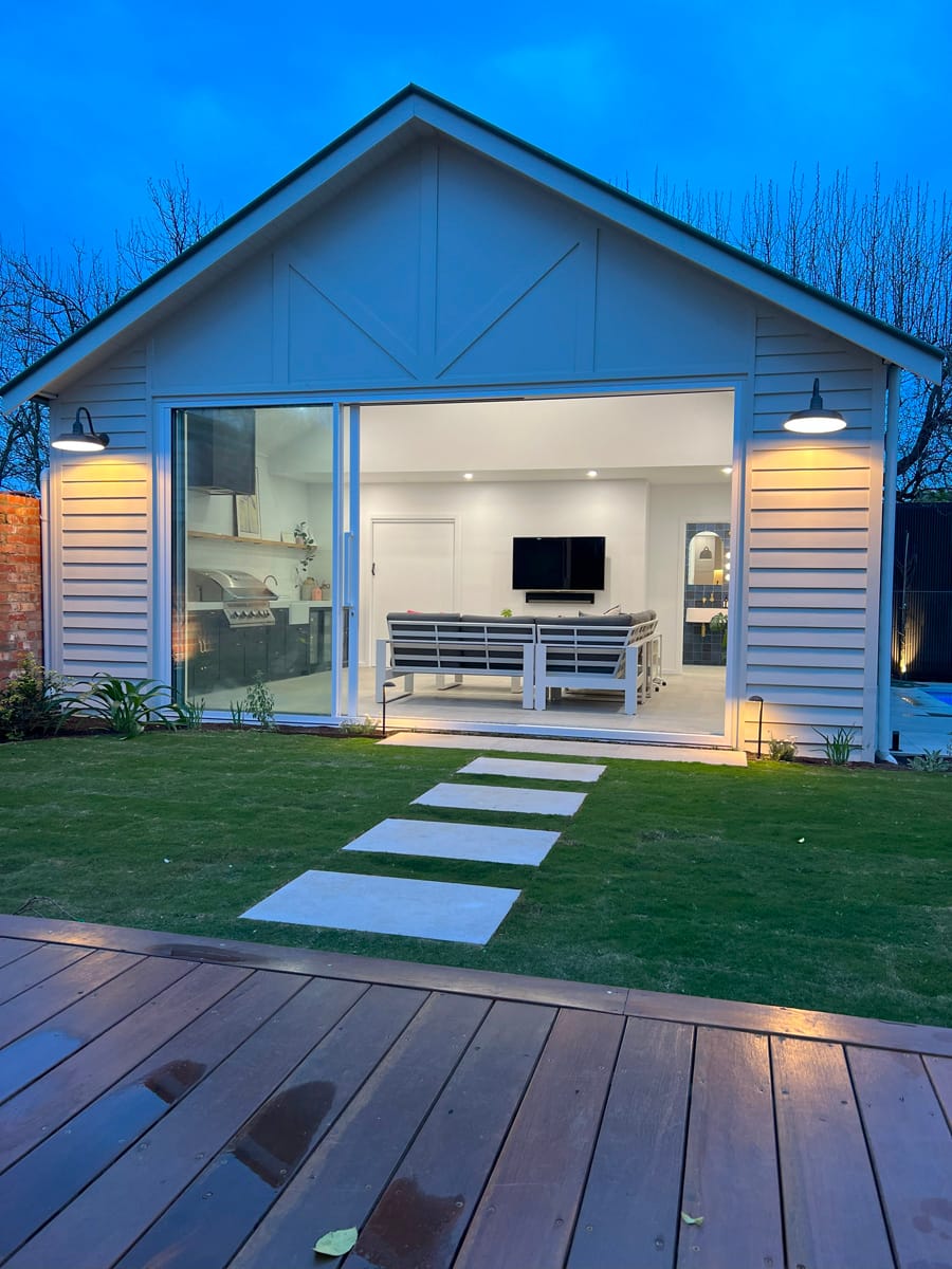 Modern house exterior with open patio, featuring a landscaped yard, stone pathway, and contemporary design elements, illustrating custom home building in Melbourne.