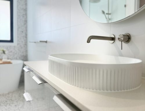 Modern bathroom sink with a sleek design, white oval basin, and stylish faucet, set against a contemporary tiled wall, emphasizing home renovation aesthetics.