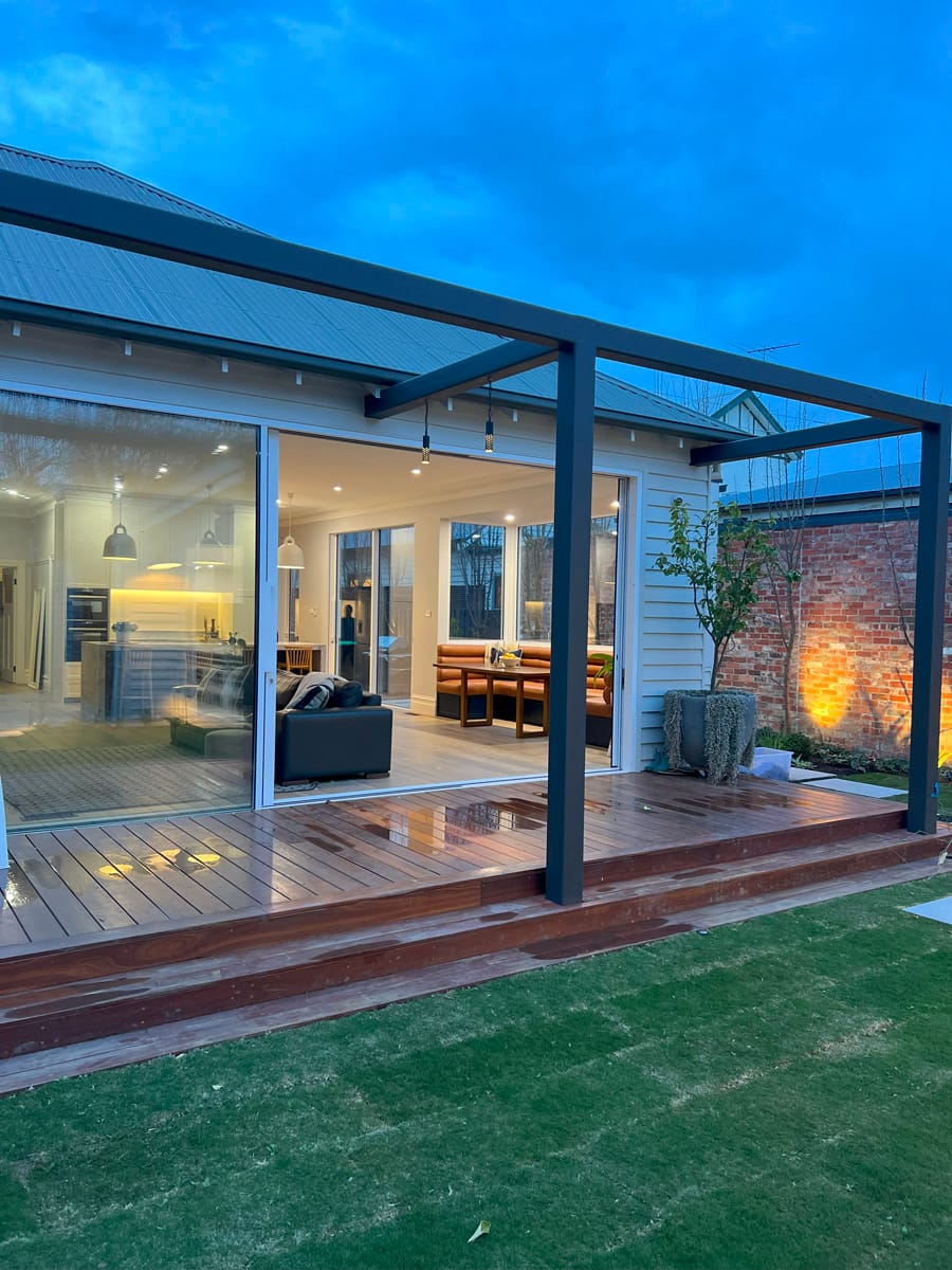 IMG_7106 Modern custom home exterior in Melbourne with open patio, wooden decking, and spacious glass windows showcasing interior design.